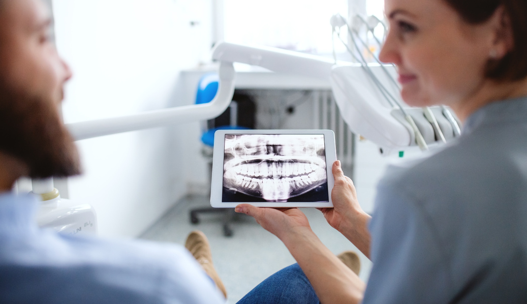 Dentist Showing Teeth X-ray to Patient